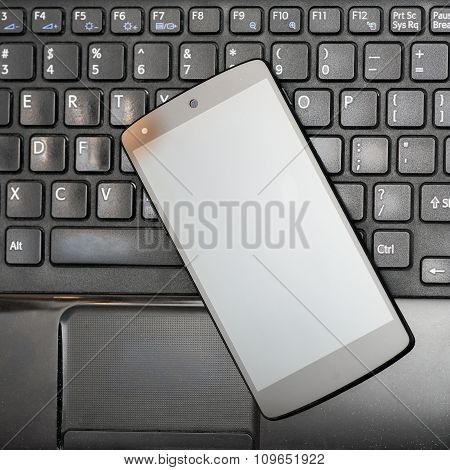 Smartphone on black laptop keyboard