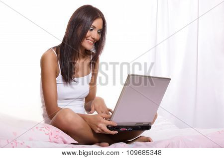 Young beautiful woman on bed using laptop