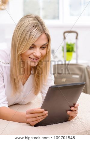 Young woman lying in bed and using her tablet.