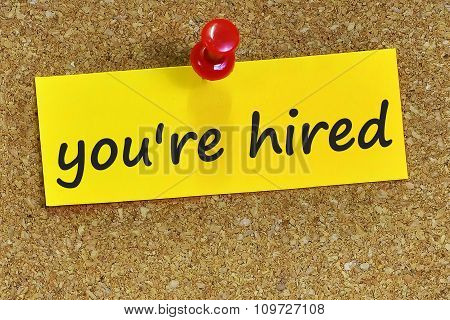 You're Hired Word On Yellow Notepaper With Cork Background