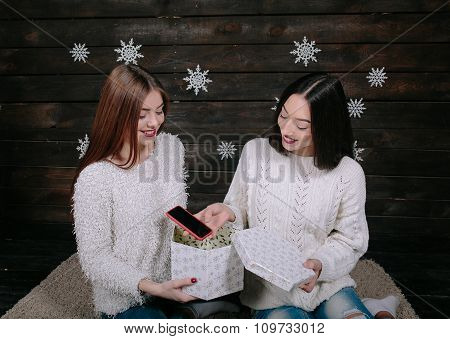 Two young girls holding holiday present