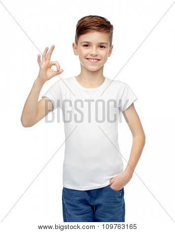 childhood, fashion, advertisement and people concept - happy boy in white t-shirt and jeans showing ok hand sign