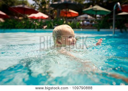 Closeup Small Blonde Girl Swims Smiles In Hotel Swimming Pool