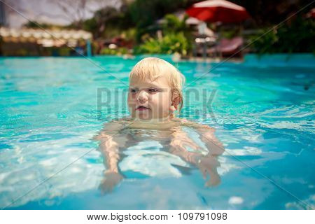 Small Girl Stands On Fours In Shallow Transparent Pool Water
