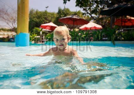 Small Blonde Girl Plays Smiles In Transparent Water Of Pool