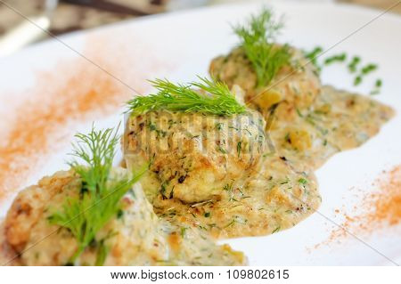 Meatballs served in a dill sauce on a white plate.