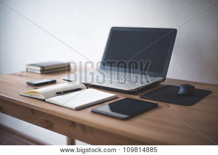 Wooden table with office supplies side view Laptop notebook tablet.