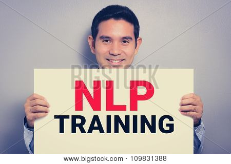 NLP TRAINING message on white cardboard held by smiling man vintage tone