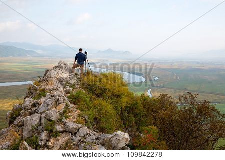 Photographer on top of a mountain landscape on the camera shoots.