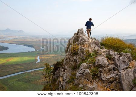 Photographer on top of mountain on the camera shoots neighborhood.