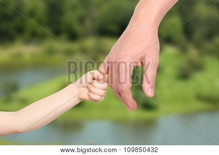 A Father  Holds The Hand Of A Small Child On A Green  Background