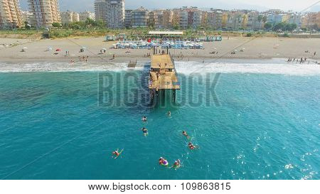 ALANIA - AUG 19, 2015: Many people swim in sea near pier on city beach at summer sunny day. Aerial view videoframe