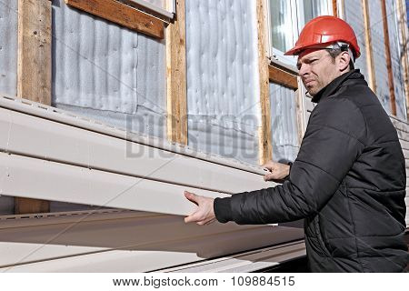 A Worker Installs Panels Beige Siding On The Facade