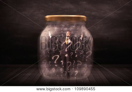 Businessman locked into a jar with question marks concept on background