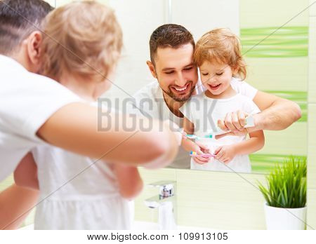 Happy Family Father And Child Girl Brushing Her Teeth In Bathroom Toothbrushes