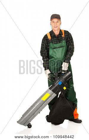 Experienced gardener in uniform with a leaf blower