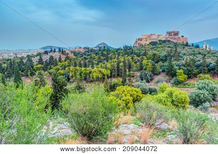 Parthenon and Herodium construction in Acropolis Hill in Athens, Greece. Beautiful landscape with green trees around ancient architecture.