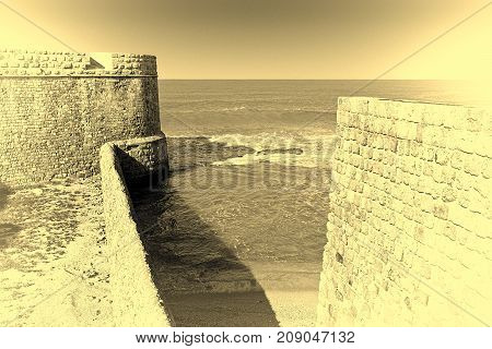 The city beach located adjacent to the sea walls of Akko in Israel. View on a fortification of an old city Akko a small Israeli port town with ruins dating 4000 years. Vintage style toned picture
