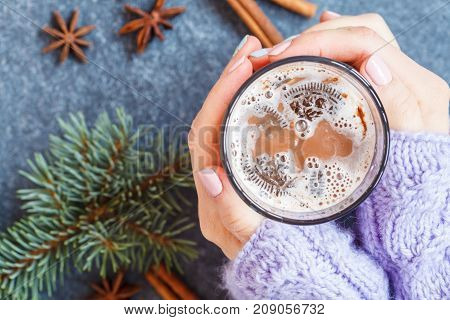 Christmas cup of cocoa in the hands of women on a background of Christmas decorations.