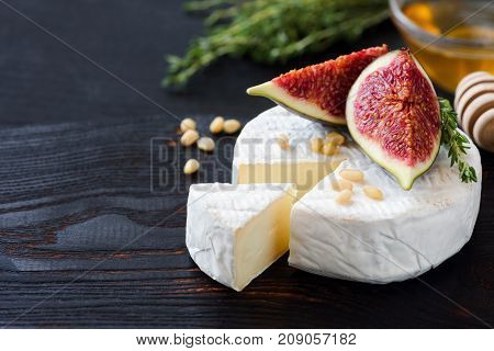White cheese brie or camambert. Gourmet appetizer cheese plate with white cheese, figs, thyme, honey and nuts