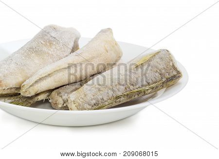 Fragment of white dish with several carcasses of the frozen saltwater fish notothenia without of a heads and tails on a white background