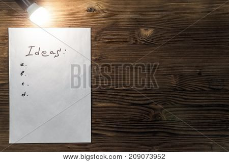 Tips note paper page on wooden desk table surface background with copy space in the light of burning bulb lamp.