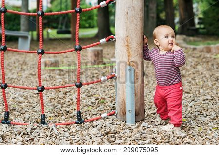 Outdoor portrait of adorable baby girl having fun on playground cute little 9-12 months child playing outdoors