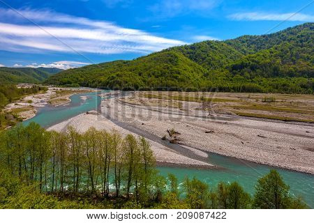 The valley of the mountain river is azure around the forests on the slopes against the background of a clear blue sky. The Shahe River near the village of Bolshoy Kimchay, Sochi.