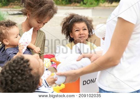 Volunteer sharing clothes and toys with poor African children outdoors
