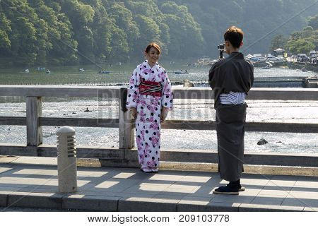 Kyoto, Japan - May 20, 2017:  Woman in kimono is phtographed on the historical Togetsukyo Bridge over the Katsura River at Otsuki, Yamanashi, Japan   