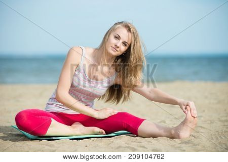 Young lady practicing yoga. Beautiful woman posing at the summer sand beach. Workout near ocean sea coast. Beautiful fit tan girl. Fitness model caucasian ethnicity outdoors. Weight loss exercise. Meditation.