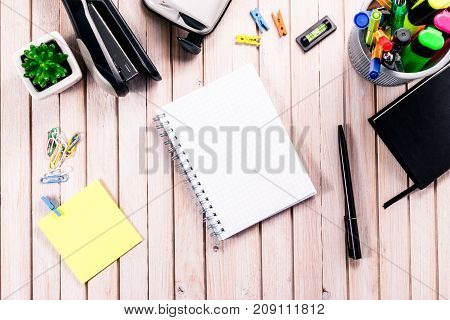 Top view workspace mockup on wooden background with blank notebook with copy space, pen, tacker, punch, clips and accessories. Overhead view. Flat lay, top view