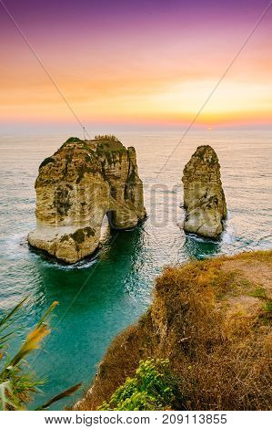 Beautiful sunset on Raouche, Pigeons' Rock. In Beirut, Lebanon.Sun and Stones are reflected in water.dense clouds in the sky.