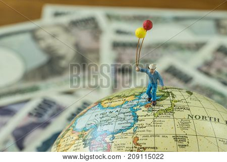 Miniature figure men holding balloons standing on north korea and japan map globe as peace and war solution concept.