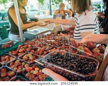 STRASBOURG FRANCE - JUN 25 2017: Customer waiting to pay for organic delicious strawberries and black currant at an open-air Saturday market in Strasbourg
