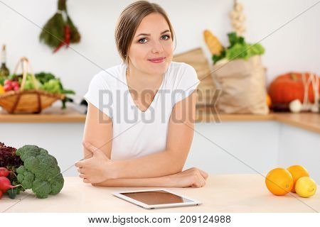 Young woman is making online shopping by tablet computer and credit card. Housewife found new recipe for cooking in a kitchen.