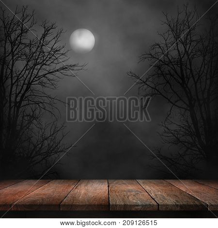 Old wood table and silhouette dead tree at night for Halloween background.