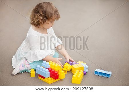 Adorable little girl play with color plastic block building and having fun. Playing with educational toys. Early building and having fun. Playing with educational toys. Early developement. Empty place for text.
