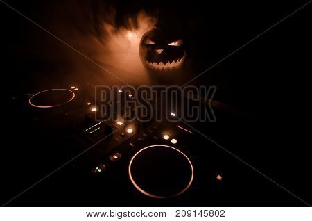 Halloween Pumpkin On A Dj Table With Headphones On Dark Background With Copy Space. Happy Halloween