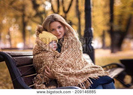 cute little boy with her mother walking in the autumn in the park in the yellow foliage and sitting in a rug
