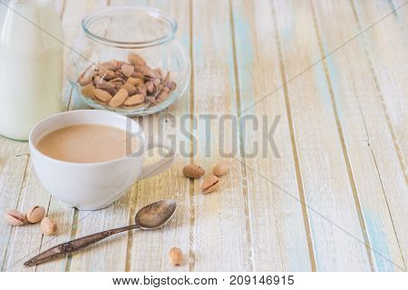 Coffee With Milk And Pistachios On Wooden Table, Copy Space