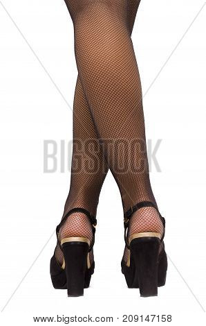 High heel shoes and black sexy fishnet pantyhose stockings on young woman legs standing on the floor isolated. Back view.