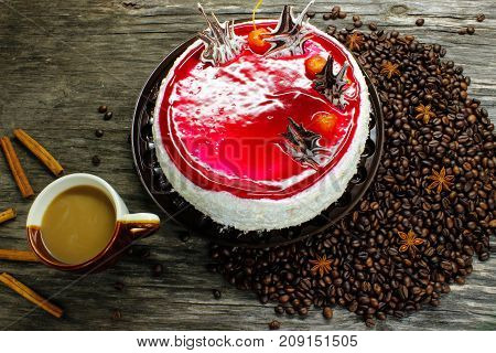 A cup of coffee with a big cake and coffee beans anise and cinnamon on a wooden table. view from above