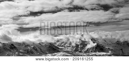 Black and white panoramic view on snow mountains and sunlight cloudy sky at winter evening. Caucasus Mountains. Svaneti region of Georgia.