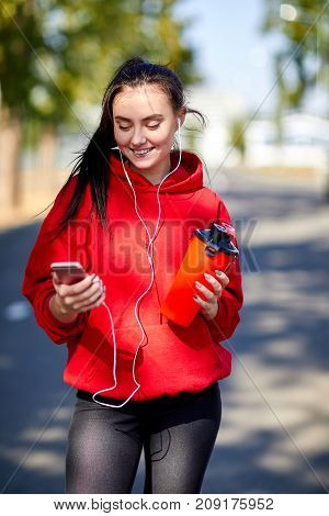 Young, beautiful girl at a warm-up in the street in the park doing muscle stretching