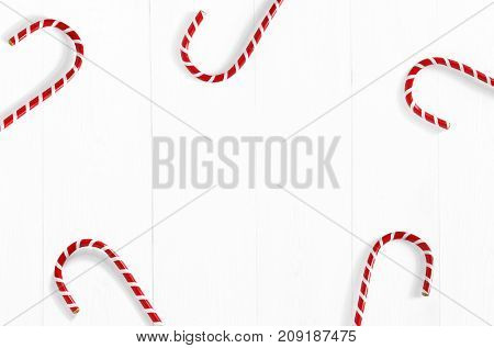 Christmas styled stock photo. White wooden background with candy cane decorations and empty space, top view. Festive composition.