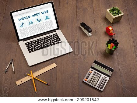Laptop computer on wooden desk with office suplies