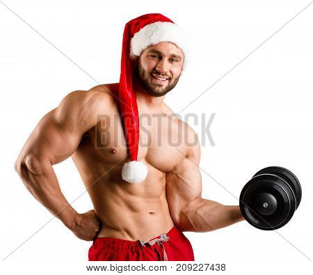 Sexual strong young newyear man with muscular body in red and white christmas santa claus hat standing posing on studio white background, vertical photo, isolated