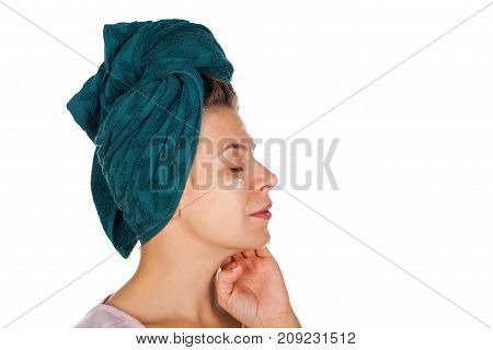 Young woman applying face moisturizer after shower wearing a towel on head - isolated background