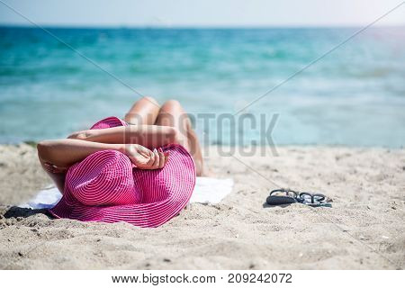 Woman in a pink hat relaxing on the beach